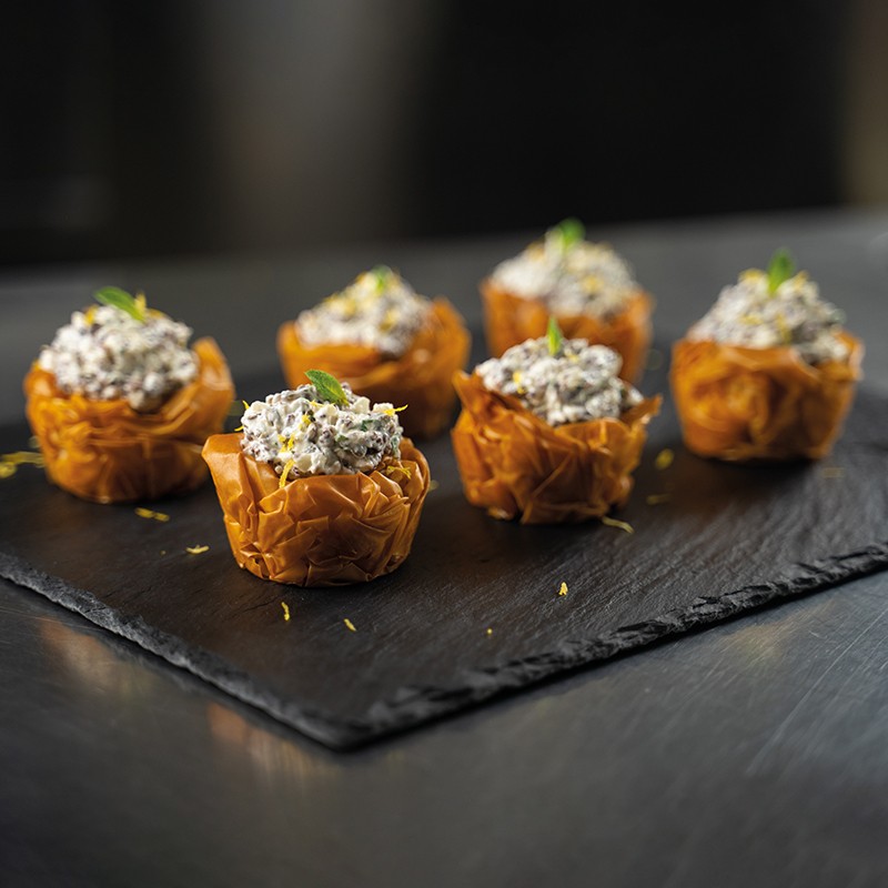 Cestini croccanti di pasta fillo ripieni di CauliPower e maionese alla menta, decorati con scorza di limone e foglie fresche.