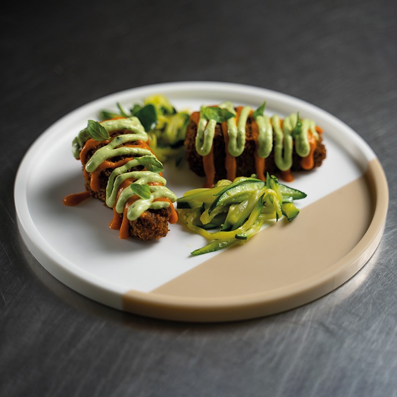 Cosciotti serviti con salsa ai pomodorini, maionese al basilico e julienne croccante di zucchine, decorati con foglie di basilico fresco